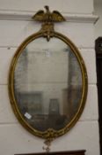 A gilt framed oval mirror with eagle cresting.