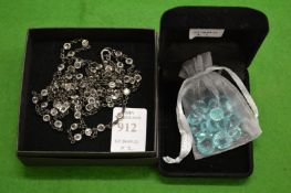 A decorative necklace and a bag of decorative stones.