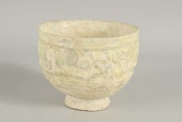 A 11TH-12TH CENTURY ISLAMIC POTTERY FOOTED BOWL, with moulded calligraphy, 15cm diameter.