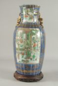 A CHINESE BLUE GROUND GILDED FAMILLE VERTE PORCELAIN VASE, on a hardwood stand, painted with two