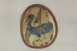 AN ISLAMIC GLAZED POTTERY TILE FRAGMENT, depicting a bird, inset within an engraved copper frame,