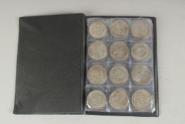 A FOLDER CONTAINING A COLLECTION OF REPLICA COINS.