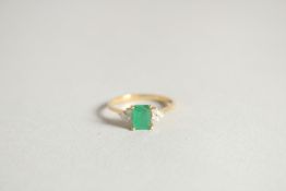 AN EMERALD AND DIAMOND THREE STONE RING.