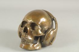 AN UNUSUAL BRASS SCULPTURE OF A SKULL WEARING HEADPHONES. 7.5ins wide.
