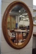 An oval mirror with carved pine frame.
