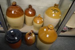 A good collection of large salt glazed wine and spirit flagons, some with impressed retailers