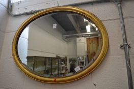 A gilt framed oval mirror.