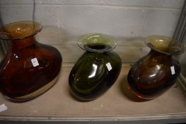 A large heavy amber colour glass vase, signed to the base together with two other similar.