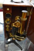 A Swift & Son brass microscope with accessories in a mahogany case.