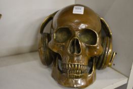 An unusual cast bronze sculpture of a skull wearing headphones.