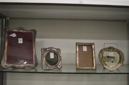 Four silver photograph frames.
