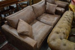 A brown leather upholstered large two seater settee.