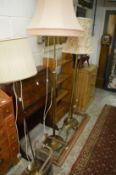 Four various brass floor standing lamps.