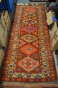 A Persian hall carpet, red ground with geometric motifs 240cm x 100cm.