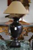 A large urn shaped black pottery table lamp.