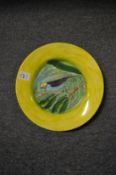 A pottery plate decorated with a bird on a branch.