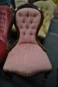 A Victorian walnut framed and button upholstered nursing chair.