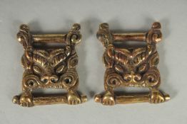 TWO TIBETAN BRONZE LION HEAD ORNAMENTS.