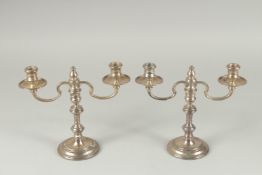 A PAIR OF SILVER TWO BRANCH CANDLESTICKS on circular bases. London 1979.