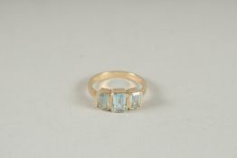 A 9CT GOLD THREE STONE EMERALD CUT BLUE TOPAZ RING.