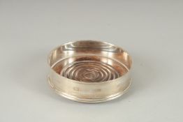 A SINGLE CIRCULAR SILVER WINE COASTERS with wooden base. 5ins diameter., London 1972.