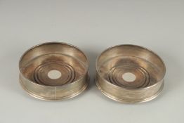 A PAIR OF CIRCULAR SILVER WINE COASTERS with wooden bases. 5ins diameter. London 1970.
