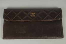 A CHANEL BROWN QUILTED PURSE with gilt double C detail. 7.25ins long.