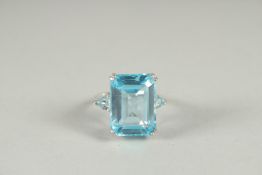 A LARGE SILVER EMERALD CUT TOPAZ RING.