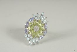 A SILVER PERIDO, TANZANITE AND TOPAZ RING.