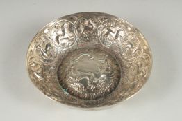 AN EASTERN WHITE METAL CIRCULAR BOWL, with a raised centre, embossed all over with animals