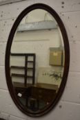 An oval mirror with carved mahogany frame.