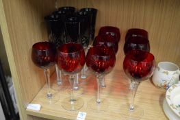 Two sets of ruby colour drinking glasses.
