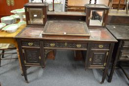 A late Victorian mahogany kneehole desk with mirrored doors and lifting writing surface to the upper