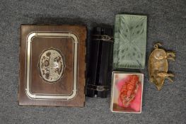 A decorative handkerchief box containing a book shaped glass paperweight, small brass pig shaped