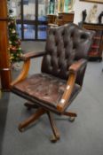 A brown leather button upholstered revolving armchair.