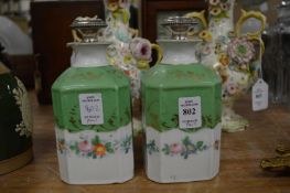 A pair of floral and gilt decorated porcelain decanters with silver stoppers.