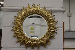 A modern gilded sunburst style wall mirror.