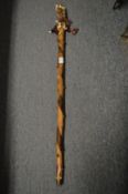 An African staff with decorative shell and woven cloth grip handle.