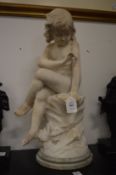 A carved marble group of a child seated on a rocky outcrop.