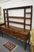 An 18th century oak dresser with delft rack, the base with three drawers on square legs.