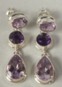 A pair of silver amethyst three drop earrings in a box.