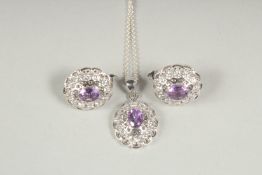 A silver amethyst pendant and chain and matching earrings in a box.