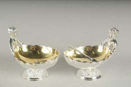 A PAIR OF SILVER PLATED CHERUB SALTS AND SPOONS.