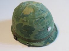 A US M1 Vietnam helmet with helmet cover with liner and chin strap.