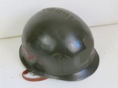 A US M1 helmet with liner and chin strap, with repainted outer shell.