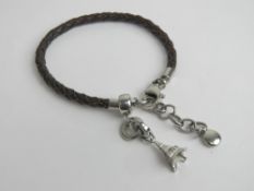 A designer charm bracelet by Fossil, braided leather with Eiffel Tower charm upon.