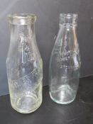 Two vintage clear glass milk bottles, one marked for Maynes Farm and Newbery Dairies St Albans.