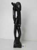 An African hard wood carving being an abstract of a man blowing a horn, standing 37cm high.