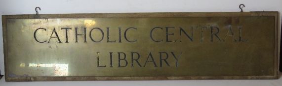 A large brass 'Catholic Central Library' sign mounted on wooden board, overall 95cm wide.