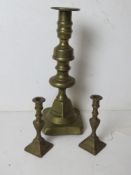 A pair of miniature brass candlesticks together with a similar full size brass candlestick.